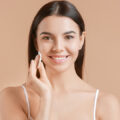 Woman with healthy skin touching her face with a cotton swab