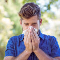 Man in a blue shirt blowing his nose